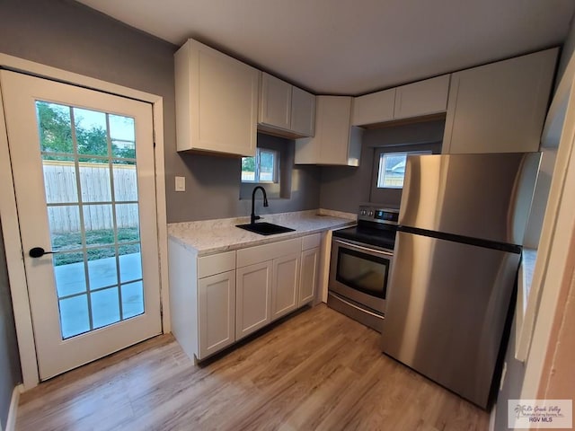 kitchen featuring white cabinetry, sink, light hardwood / wood-style flooring, and stainless steel appliances