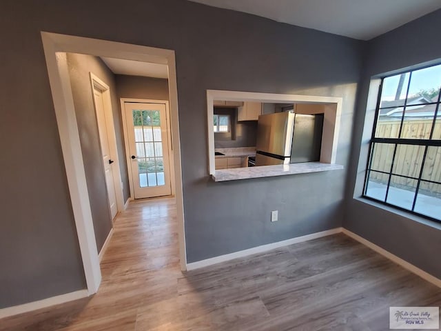 kitchen with light hardwood / wood-style floors, stainless steel refrigerator, and kitchen peninsula