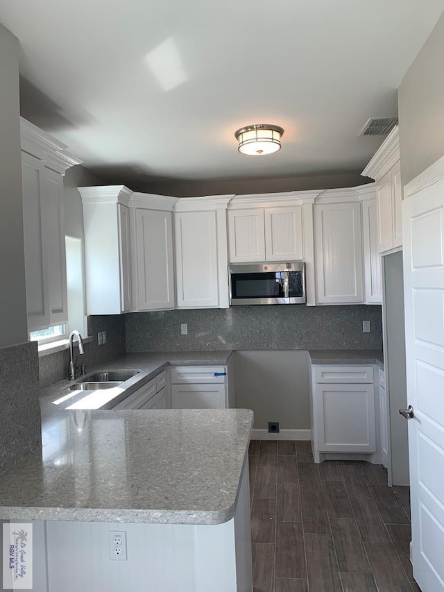 kitchen featuring sink, tasteful backsplash, dark hardwood / wood-style floors, kitchen peninsula, and white cabinets