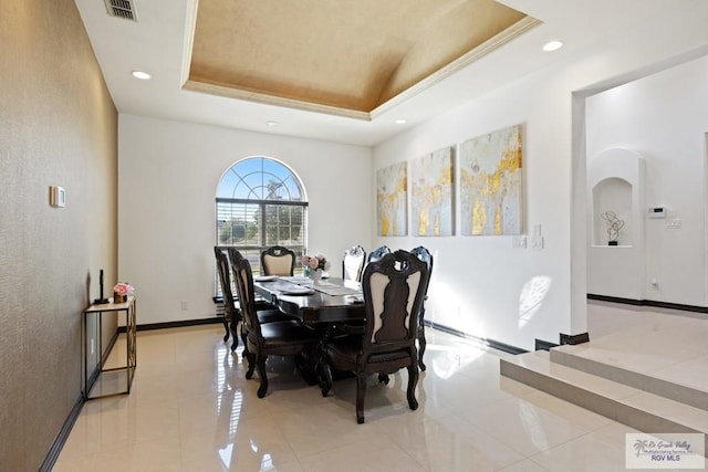 tiled dining area with a raised ceiling