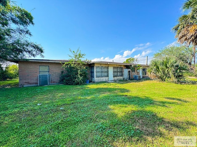 rear view of house with a lawn and central AC unit