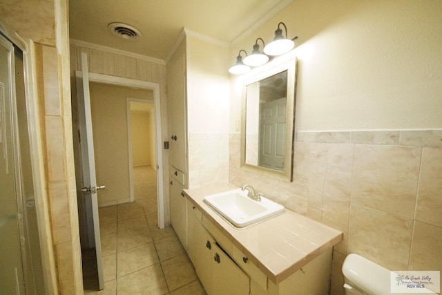 bathroom featuring toilet, visible vents, tile walls, ornamental molding, and tile patterned floors