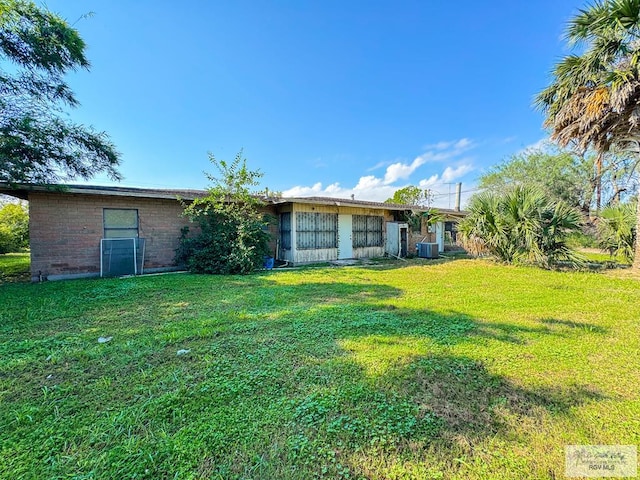 back of property with central AC and a lawn