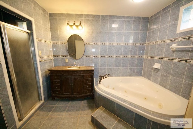 bathroom with vanity, tile walls, tile patterned floors, a tub with jets, and a stall shower