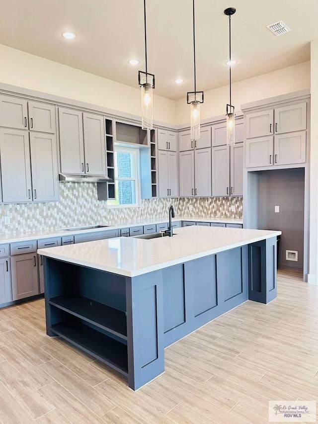 3414 Bryan Dr, Harlingen, TX 78550 - kitchen with visible vents, open shelves, light countertops, a kitchen island with sink, and gray cabinets