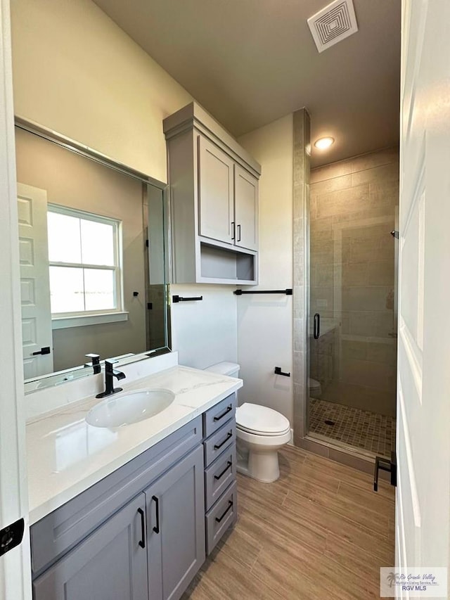 3414 Bryan Dr, Harlingen, TX 78550 - bathroom with toilet, wood finished floors, visible vents, a shower stall, and vanity