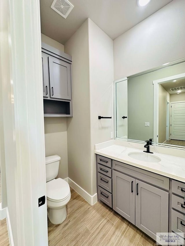 3414 Bryan Dr, Harlingen, TX 78550 - bathroom featuring toilet, visible vents, wood finished floors, and vanity