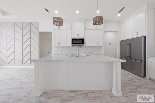 9817 Heights N, Harlingen, TX 78552 - kitchen featuring appliances with stainless steel finishes, decorative backsplash, white cabinets, a sink, and a center island with sink