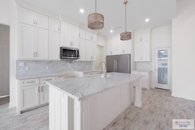 9817 Heights N, Harlingen, TX 78552 - kitchen with stainless steel appliances, a sink, tasteful backsplash, a kitchen island with sink, and white cabinetry