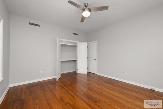 unfurnished bedroom with dark wood-style floors, visible vents, baseboards, and ceiling fan