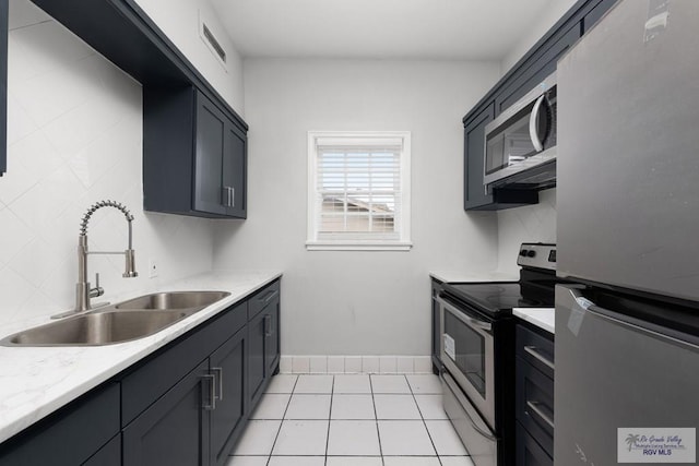 kitchen featuring light tile patterned floors, stainless steel appliances, tasteful backsplash, visible vents, and a sink