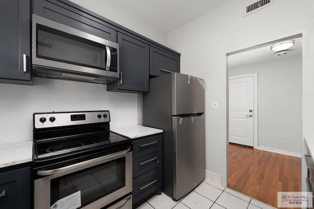 kitchen with dark cabinets, visible vents, stainless steel appliances, and decorative backsplash