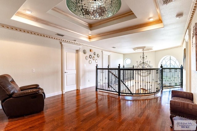 interior space featuring crown molding, a notable chandelier, a tray ceiling, and wood-type flooring