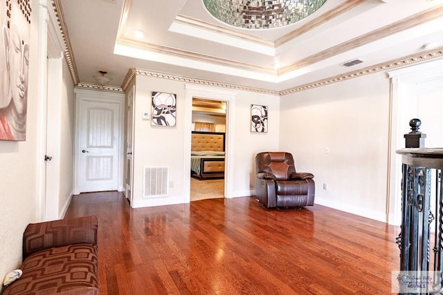 living area with hardwood / wood-style flooring, ornamental molding, and a raised ceiling