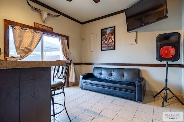 tiled living room with ornamental molding and ceiling fan