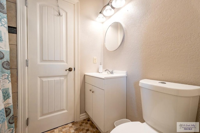 bathroom featuring walk in shower, vanity, and toilet