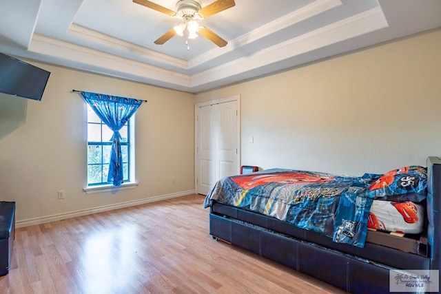 bedroom featuring ceiling fan, ornamental molding, a raised ceiling, and light hardwood / wood-style floors