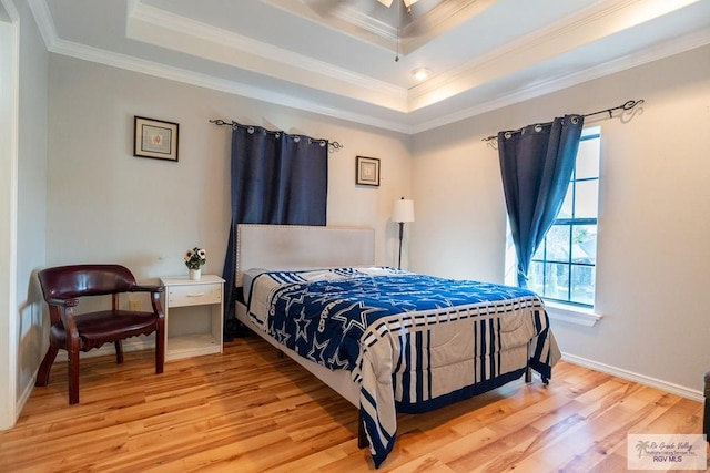 bedroom featuring crown molding, wood-type flooring, and a tray ceiling