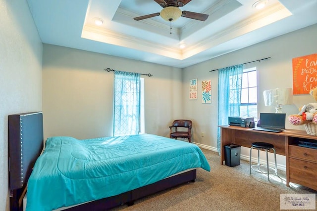 carpeted bedroom with ceiling fan and a raised ceiling