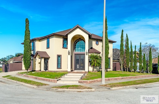 mediterranean / spanish-style home featuring a front lawn and french doors