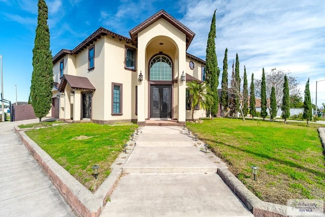 mediterranean / spanish-style home featuring a front lawn and french doors