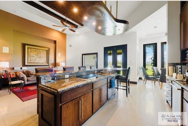 kitchen featuring a kitchen island, light tile patterned flooring, beam ceiling, and french doors