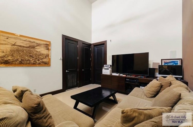 living room featuring a towering ceiling and light colored carpet