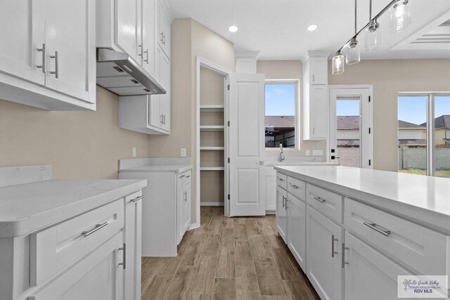 5112 Blackhawk Ave, Rio Grande City, TX 78582 - kitchen with under cabinet range hood, light countertops, plenty of natural light, and white cabinets