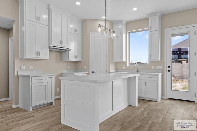 5112 Blackhawk Ave, Rio Grande City, TX 78582 - kitchen with a center island, white cabinetry, baseboards, light countertops, and light wood-style floors