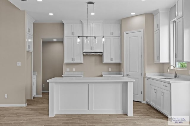 5112 Blackhawk Ave, Rio Grande City, TX 78582 - kitchen featuring white cabinetry, light wood finished floors, a center island, and a sink