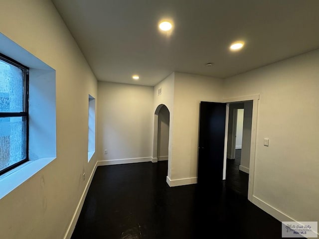 empty room with arched walkways, baseboards, and recessed lighting