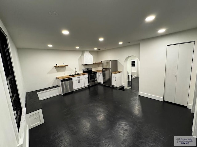 kitchen with arched walkways, stainless steel appliances, a sink, and recessed lighting