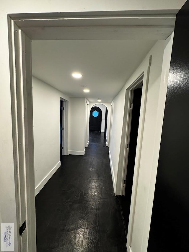 hallway with arched walkways and baseboards