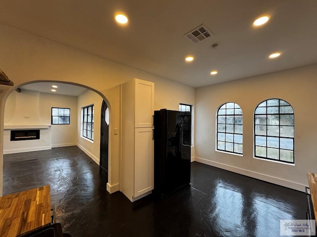 kitchen featuring visible vents, arched walkways, black refrigerator with ice dispenser, white cabinetry, and recessed lighting