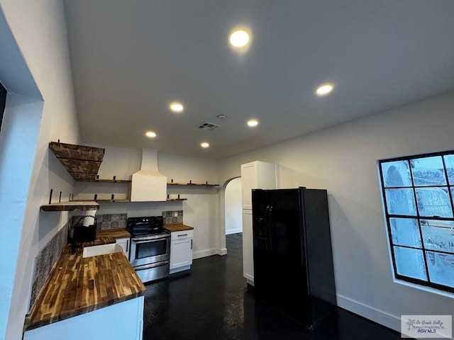 kitchen with arched walkways, open shelves, butcher block counters, black refrigerator with ice dispenser, and stainless steel range with electric stovetop