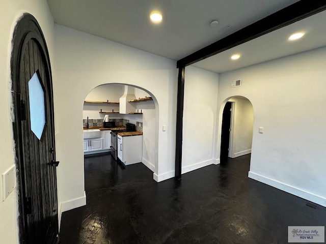 interior space featuring baseboards, visible vents, arched walkways, beamed ceiling, and recessed lighting