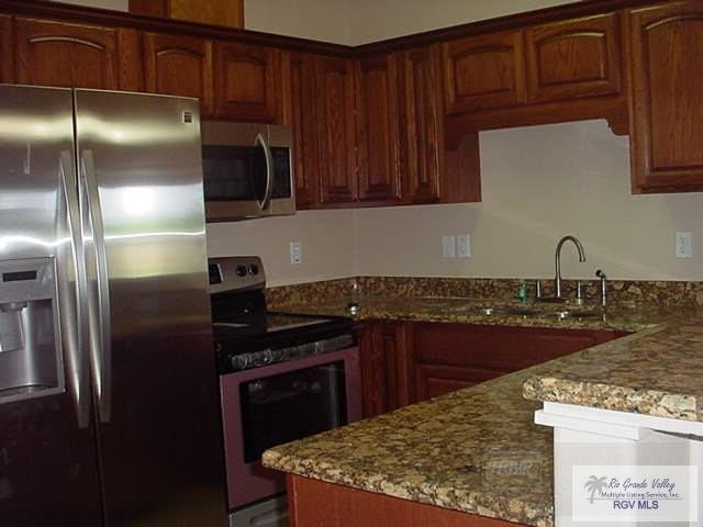 kitchen featuring light stone countertops, sink, and stainless steel appliances