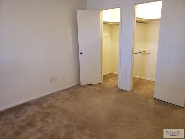 unfurnished bedroom featuring a spacious closet, carpet floors, and a closet