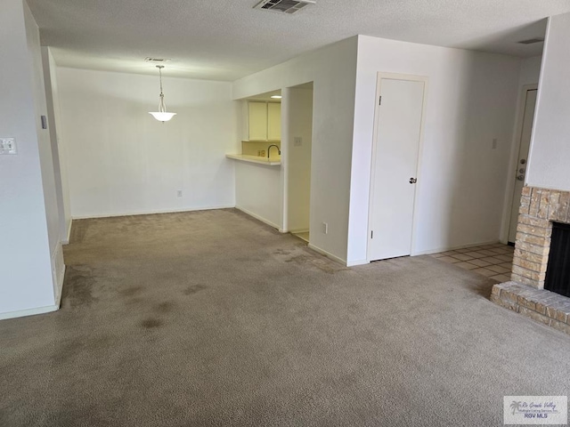 unfurnished living room featuring a fireplace, a textured ceiling, and carpet floors