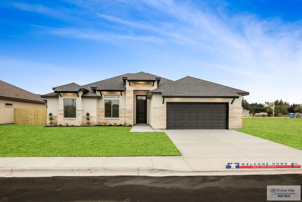 2609 Marky St, Harlingen, TX 78552 - prairie-style home featuring stone siding, an attached garage, concrete driveway, and a front yard