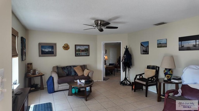 living room with visible vents, a ceiling fan, a textured ceiling, light tile patterned floors, and baseboards