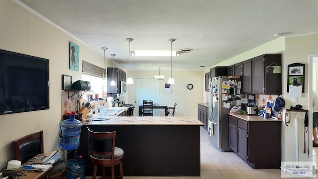 kitchen with light tile patterned flooring, hanging light fixtures, stainless steel appliances, and ornamental molding