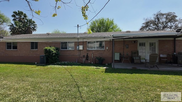 rear view of house featuring a patio, a lawn, brick siding, and french doors