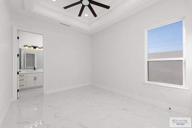 spare room featuring a tray ceiling, ceiling fan, crown molding, and sink