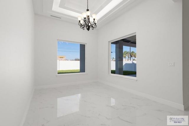 unfurnished room with a tray ceiling and a chandelier