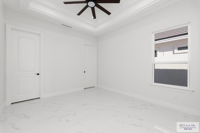 spare room with a tray ceiling, crown molding, and ceiling fan