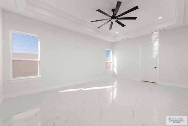 unfurnished room with a raised ceiling, ceiling fan, and ornamental molding