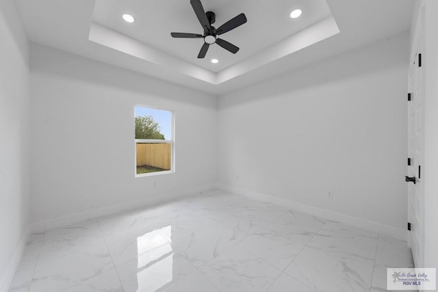 spare room featuring a tray ceiling and ceiling fan