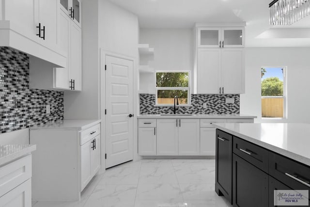 kitchen featuring white cabinets, decorative light fixtures, sink, and tasteful backsplash