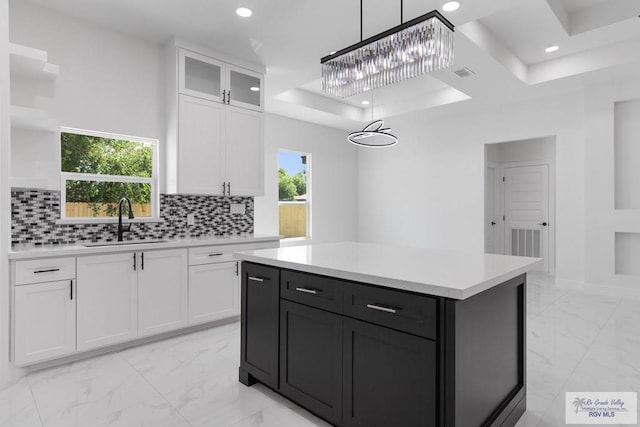 kitchen featuring white cabinetry, a center island, sink, hanging light fixtures, and tasteful backsplash